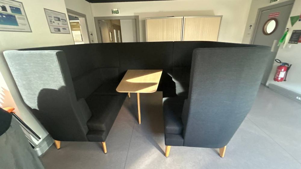 Ensemble de mobilier de réunion composé de banquettes à haut dossier formant un espace semi-fermé avec table centrale